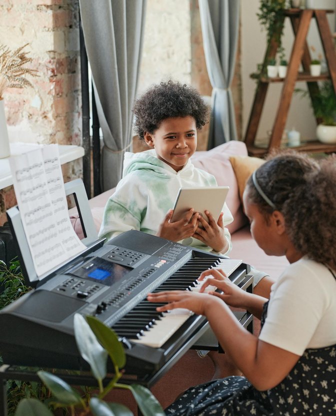 Two children playing keyboard together during a piano lesson